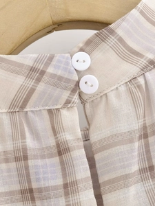 Detail view of plaid shirt back collar with double white buttons and neat sewing finish