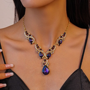 Close-up of golden necklace with purple teardrop crystals and pavé diamonds on a model