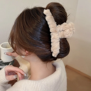 Detail of plush beige faux fur hair claw clip styled on a woman's hair in winter vibe