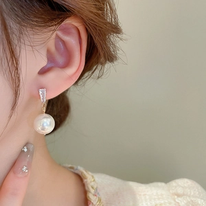 Close-up of elegant pearl drop earring with rectangular zircon on woman ear