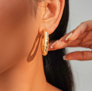 Detail of golden bamboo style hoop earring worn by a model in a close-up professional shot