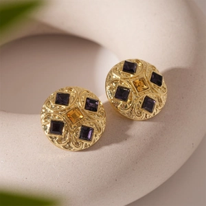 Detail of vintage gold earrings with embossed patterns and purple gemstone inlays