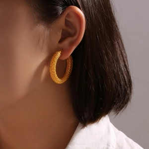 Orecchini a cerchio a U placcati in oro con trama a maglia intrecciata su una modella