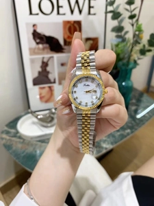 Detail of two-tone stainless steel watch band and calendar window on white dial