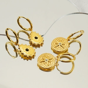 Golden earrings with drop and round turquoise stones on a reflective mirror surface