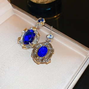 Macro shot of oval blue sapphire earrings with vintage baroque gold and silver frames