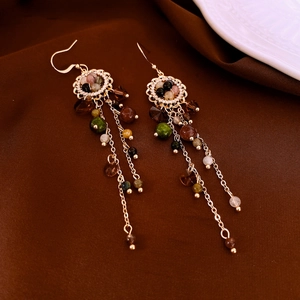 Macro detail of vintage gold flower tassel earrings with multi-color faceted beads