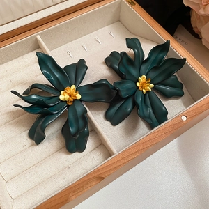 Detailed view of dark green acrylic flower earrings with yellow beads in a jewelry box