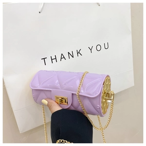 Detail of purple cylindrical bag with quilted pattern, gold chain and pearl accents
