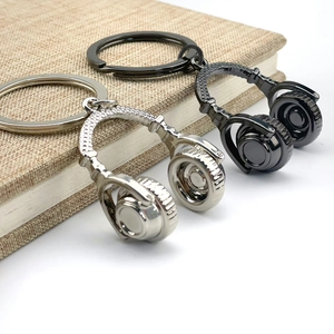 Creative headphone keychain in silver and black metal on a textured fabric book surface