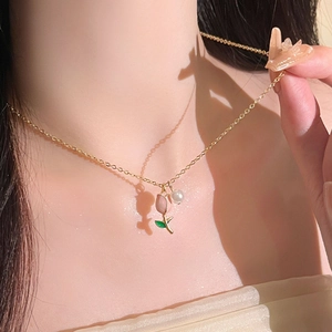 Close-up of a gold tulip pendant and white pearl on an elegant necklace for women