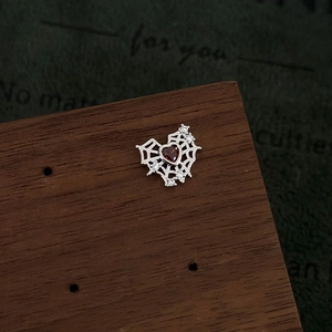 Macro detail of silver spider web stud earring with red heart gemstone and zircons