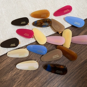 Gros plan de pinces à cheveux élégantes en acrylique coloré avec texte France Handmade