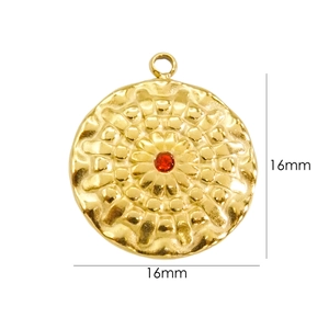 Close-up of a 16mm hammered 14K gold plated flower pendant with a central red gemstone