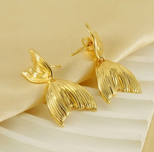 Detailed view of gold fish tail earrings with radial texture on a satin background