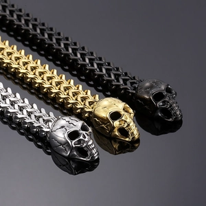 Detail of punk skull bracelets in silver, gold and black with double-layer metal weave