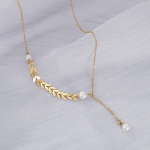 Detail of gold leaf pendant with three pearls on a silk background necklace