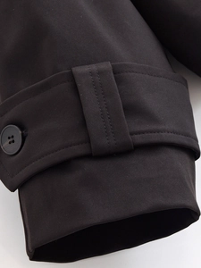 Detailed close-up of double-breasted trench coat cuff with twill fabric and button