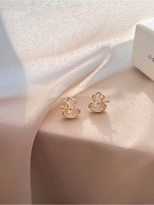 Close-up of gold-plated gourd earrings with zircons on silk background for a luxury look