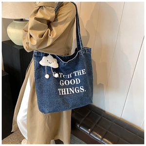Detail van donkerblauwe denim shopper met tekstbedrukking en wolk-accessoire
