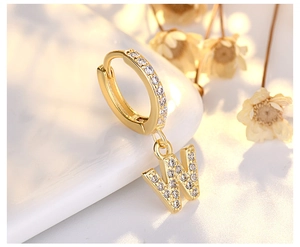 Macro view of gold S925 silver letter W earring with shimmering pavé cubic zirconia