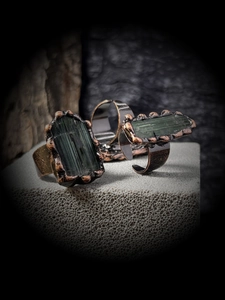 Macro shot of irregular deep green tourmaline raw stones set in vintage copper rings