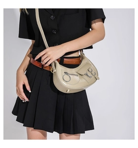 Détails du sac hobo beige avec anneaux métalliques et accents de style punk moto