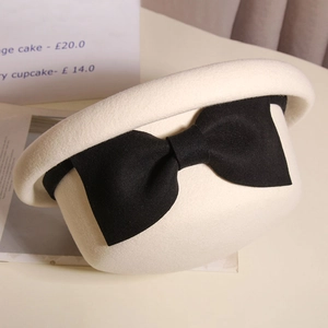 Detailed close-up of cream wool felt hat with an elegant large black ribbon bow
