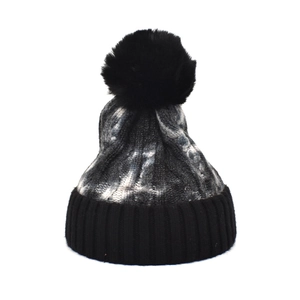 Detailed macro shot of the black and gray tie-dye knit pattern and fuzzy pom-pom top