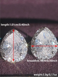 Macro shot of silver teardrop stud earrings with size annotations on purple velvet