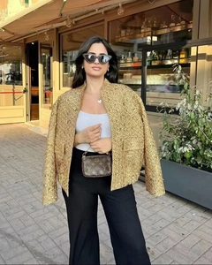 Scatto all'aperto di una lussuosa giacca in tweed dorato con paillettes e collo alto