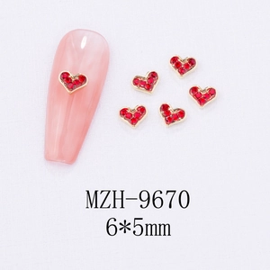 Detail of 6x5mm red heart nail art charm with gold alloy frame on pink manicure