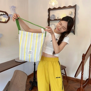 Détail du sac cabas en toile à rayures jaunes et bleues avec une bandoulière verte