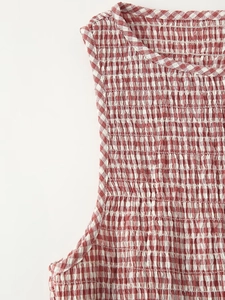 Detail of red and white gingham fabric with smocked elastic texture on the dress