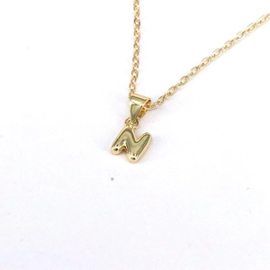 Macro shot of gold initial N pendant showcasing polished metal texture and smooth edges