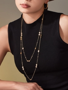 Close-up of long gold layered necklace with sparkling cubic zirconia on a black top