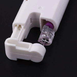 Macro detail of disposable ear piercing tool with white plastic body and sterile needle