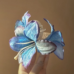 Detail van een blauw en paars gradiënt lelie haarklem met zijden bloem textuur