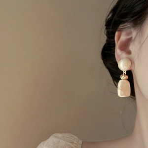 Close-up of vintage cream resin earrings with marble pattern on a female model