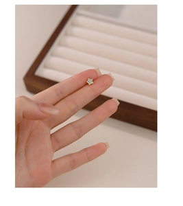 Close-up of tiny S925 sterling silver star stud earrings with gold finish and micro-inlay