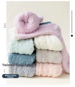 Macro view of plush coral fleece socks featuring cable knit patterns in soft pastel colors