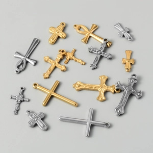 Flat lay of vintage gold and silver stainless steel cross and ankh charm pendants