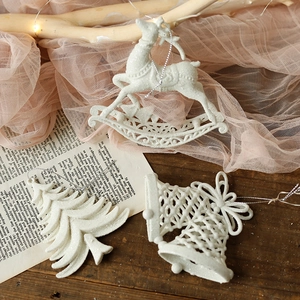 White glitter Christmas tree ornaments featuring reindeer and bell shapes on wood