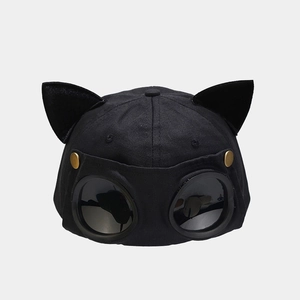 Close-up of black baseball cap with cat ears, aviator goggles, and gold metal accents