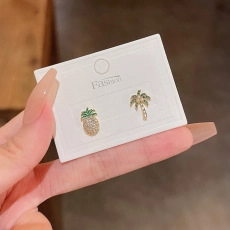 Detail of tropical pineapple and palm tree stud earrings with sparkling rhinestones