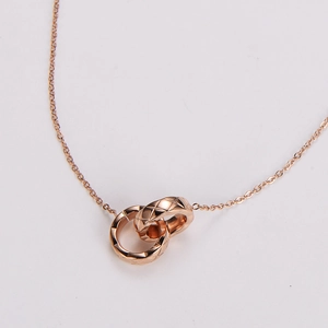 Detailed view of rose gold interlocking rings with quilted pattern on a delicate necklace