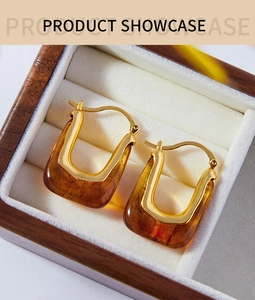 Macro view of gold-plated U-shaped earrings with amber resin in a wooden gift box
