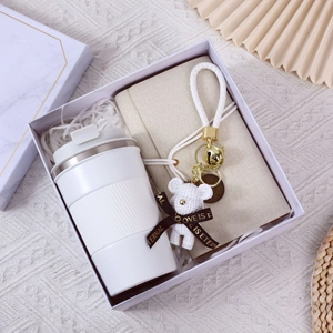 Business gift set with white thermal cup, beige notebook and plush bear in marble box