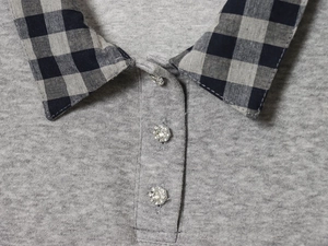 Close-up of grey knit top with plaid collar and floral rhinestone buttons detail