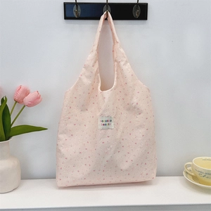Gros plan du sac cabas rose à fleurs avec détails gaufrés et étiquette de marque